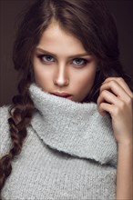 Beautiful young girl with gentle make-up in warm sweater and long straight hair. Beauty face. Studio portrait