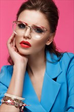 Beautiful girl in blue suit on pink background with creative make-up and fashionable style. Beauty face. Photo taken in the studio