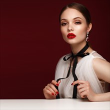 Beautiful girl in white dress with classic make-up and red manicure. Beauty face. Photo taken in the studio