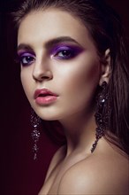 Beautiful girl with bright purple make-up and jewelery. Beauty face. Picture taken in the studio