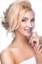 Beautiful blond girl in the image of a bride with flowers in her hair. Picture taken in the studio on a white background. Beauty face. Wedding image