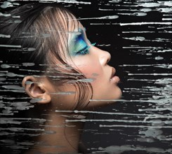 Beautiful Asian girl with bright blue make-up behind glass with drops of wax. Beauty face. Picture taken in the studio on a black background