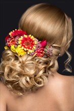 Portrait of a beautiful blond woman in the image of the bride with flowers in her hair. Picture taken in the studio on a black background. Beauty face and Hairstyle back view