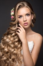 Portrait of a beautiful blond woman in the image of the bride with flowers in her hair. Picture taken in the studio on a black background. Beauty face and Hairstyle