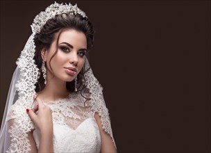 Beautiful brunette girl in the image of the Arab bride in a wedding dress and a crown on her head. Beauty face. Picture taken in the studio