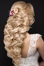 Portrait of a beautiful blond girl in image of the bride with purple flowers on her head. Beauty face. Hairstyle back view. Photo shot in the Studio on a grey background