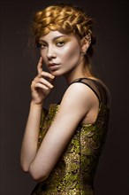 Beautiful girl in a gold dress with creative makeup and braids on her head. The beauty of the face. Photos shot in the studio