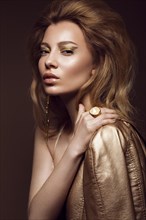 Beautiful girl in a gold dress with creative makeup and hair. The beauty of the face. Photos shot in the studio