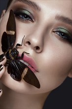 Portrait of beautiful girl with colorful make-up and cicada. Beauty face. Photo taken in the studio