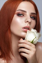 Beautiful red-haired girl with a classic make-up and rose in her hands. Beauty face. Photo taken in studio