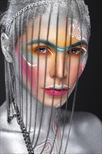 Beautiful girl in an unusual winter look with colorful face. Creative make up. Art look. Photo taken in studio