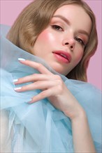 Beautiful girl with light make-up and gentle manicure in blue clothes. Beauty face. Design nails. Photo taken in studio on pink background