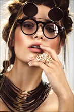 Beautiful fashion woman with creative make-up and hairstyle wearing glasses and jewelry. The beauty of the face. Photos shot in the studio