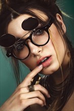 Beautiful fashion woman with creative make-up and hairstyle wearing glasses and jewelry. The beauty of the face. Photos shot in the studio