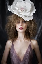 Beautiful girl with curly hair in lingerie with large flower. The beauty of the face. Photos shot in studio