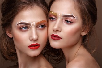 Two girls are twin sisters with an unusual eyebrow makeup. Beauty face. Photo taken in the studio