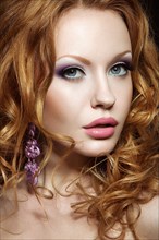 Beautiful red-haired girl with bright makeup and curls. Picture taken in the studio on a black background