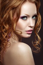 Beautiful red-haired girl with bright makeup and curls. Picture taken in the studio on a black background