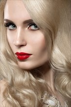Beautiful blonde woman with evening make-up and red lips. Picture taken in the studio on a black background