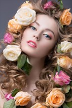 Beautiful girl with a lot of flowers in their hair and bright pink make-up. Spring image. Beauty face. Picture taken in the studio on a grey background