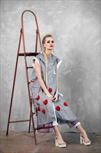 Creative unusual blond girl in designer clothes and braids on her head posing in the studio
