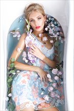 Beautiful girl in a summer dress in the bathroom with flowers. Beauty face. Photo taken in the studio