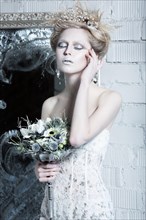 Beautiful girl in white dress in the image of the Snow Queen with a crown on her head. Picture taken in the studio with decorations