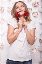 Valentines Day. Funny beautiful Woman holding candy in the form of heart. Beauty face. Picture taken in the studio with decorations