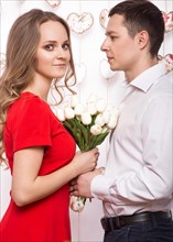 Beautiful young couple in love with a bouquet of flowers. Valentine's Day. Picture taken in the studio
