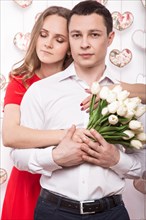 Beautiful young couple in love with a bouquet of flowers. Valentine's Day. Picture taken in the studio