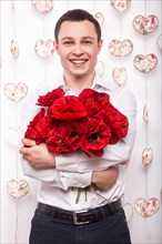 Beautiful young man in love with a bouquet of flowers. Valentine's Day. Picture taken in the studio
