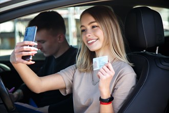 Happy smiling girl takes a selfie with a new drivers license