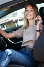 Happy smile girl in a new car with keys in her hand. Lifestyle