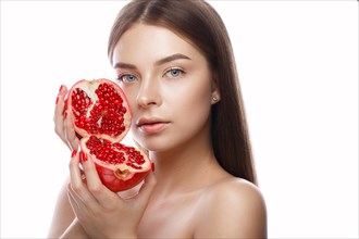 Beautiful young girl with a light natural make-up and perfect skin with pomegranate in her hand. Beauty face. Picture taken in the studio on a white background
