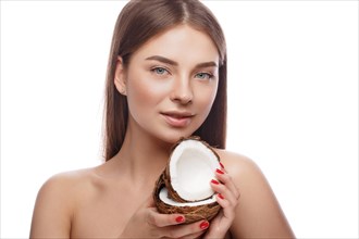 Beautiful young girl with a light natural make-up and perfect skin with coconut in her hand. Beauty face. Picture taken in the studio on a white background