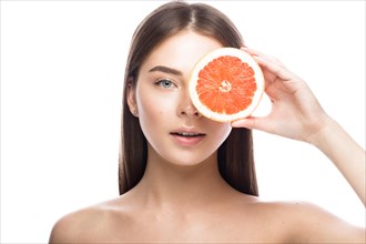 Beautiful young girl with a light natural make-up and perfect skin with Grapefruit in her hand. Beauty face. Picture taken in the studio on a white background