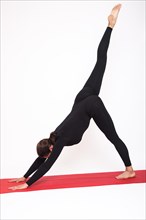 Beautiful athletic girl in a black suit doing yoga. Eka Pada Adho Mukha Svanasana asanas