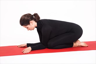Beautiful athletic girl in a black suit doing yoga. karenukasana asana