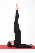 Beautiful athletic girl in a black suit doing yoga. salamba sarvangasana asana