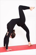 Beautiful athletic girl in a black suit doing yoga. chakrasana