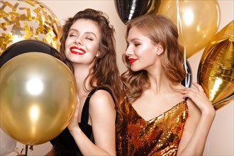 Beautiful young women in elegant evening dresses with festive balloons. Beauty face. Photo taken in the studio