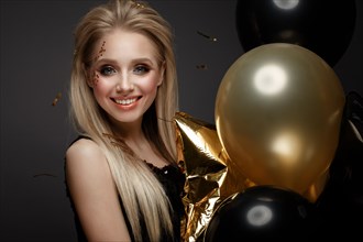 Beautiful young girl in elegant evening dress with festive balloons. Beauty face. Photo taken in the studio