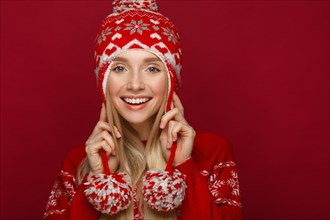 Beautiful blonde girl in a New Year's image in warm hat and sweater. Beauty face with festive makeup. Photo taken in the studio