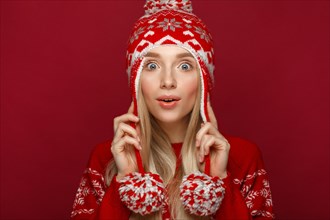 Beautiful blonde girl in a New Year's image in warm hat and sweater. Beauty face with festive makeup. Photo taken in the studio