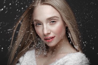 Beautiful blonde girl in a winter image with snow. Beauty face. Photo taken in the studio