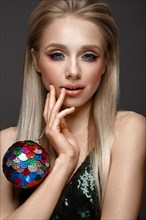Beautiful young girl in elegant evening dress with festive christmas ball. Beauty face. Photo taken in the studio