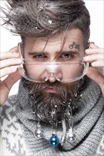 Funny bearded man in a New Year's image with snow and decorations on his beard. Feast of Christmas. Photos shot in the studio