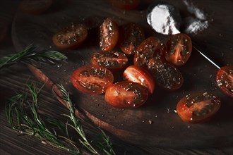 Cherry tomatoes on a wooden board with seasoning and herbs