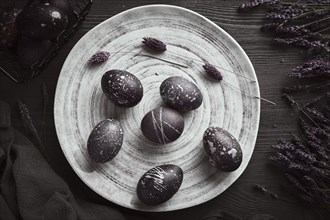 Black painted eggs for Easter on a blue plate