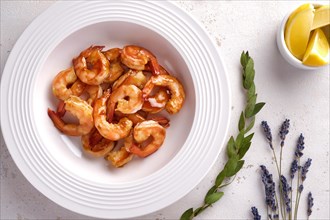 Fried shrimps in garlic sauce on a white plate with lemon